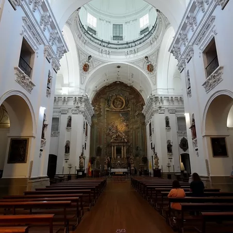 Nave central con bóveda elevada y bancos de madera alineados.