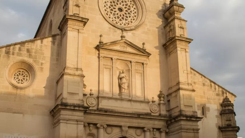 Entrada monumental de iglesia con gran rosetón y hornacina central.