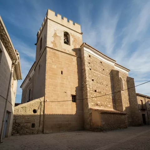 Iglesia de piedra con torre cuadrada y cielo despejado.