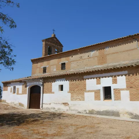 Pequeña iglesia de ladrillo y cal blanca junto a un camino
