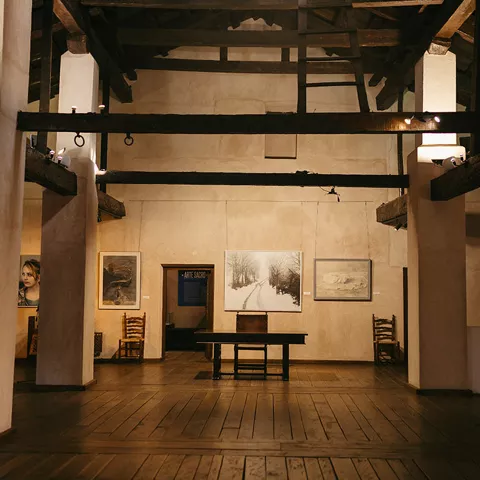 Sala expositiva con obras de arte y estructura de vigas