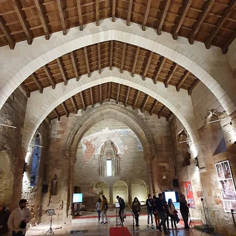 Interior amplio con bóvedas, exposiciones y visitantes.