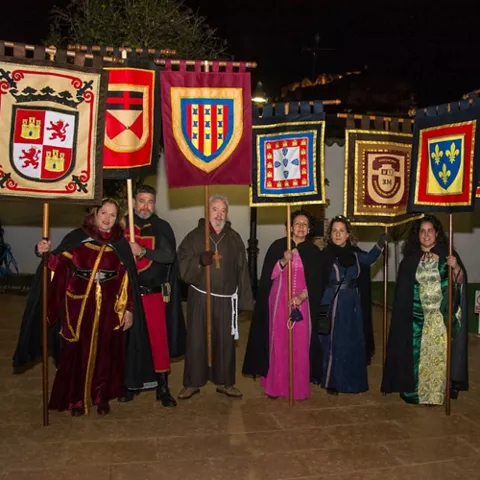 Personas con trajes medievales y estandartes nocturnos