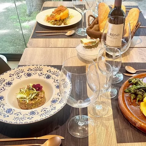 Mesa servida con carne, verduras y vino en un comedor moderno.