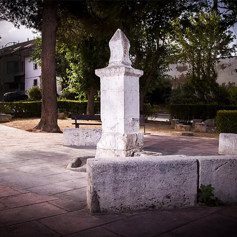 Fuente de piedra en una pequeña plaza ajardinada