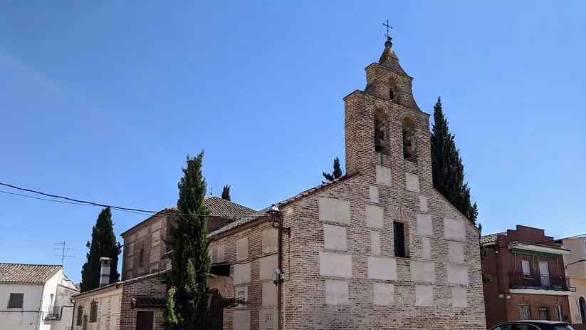 Iglesia de ladrillo con espadaña y cipreses