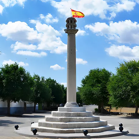 Columna de piedra con bandera en una plaza arbolada