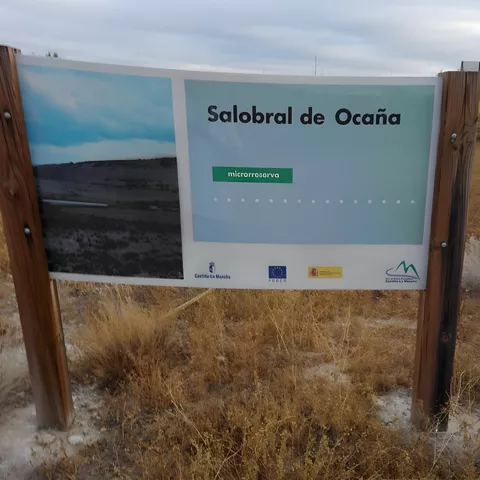 Cartel informativo en paisaje de pasto seco