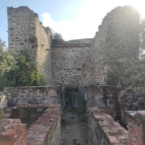 Pasillo entre muros de piedra de una edificación en ruinas