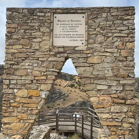 Arco de piedra con mirador y pasarela de madera.