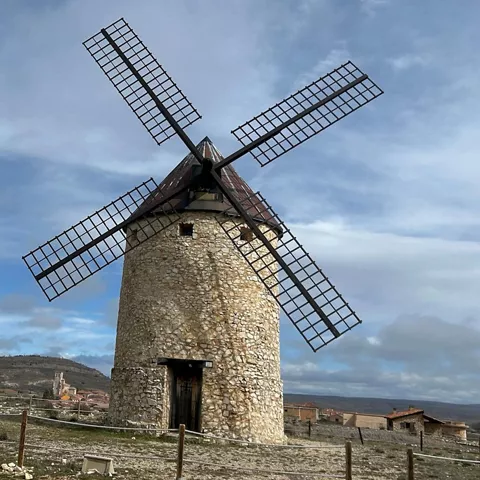 Molino de viento restaurado con aspas negras junto al casco urbano.