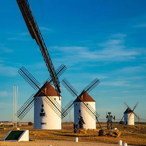 Molinos de viento alineados vistos entre aspas en primer plano.