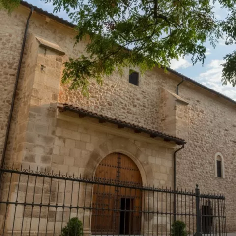 Detalle de entrada con arco de piedra y puerta de madera bajo ramas de un árbol.