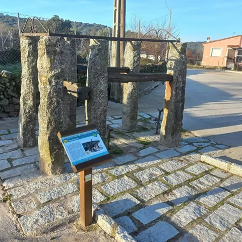 Estructura tradicional de piedra con cartel informativo junto a la carretera