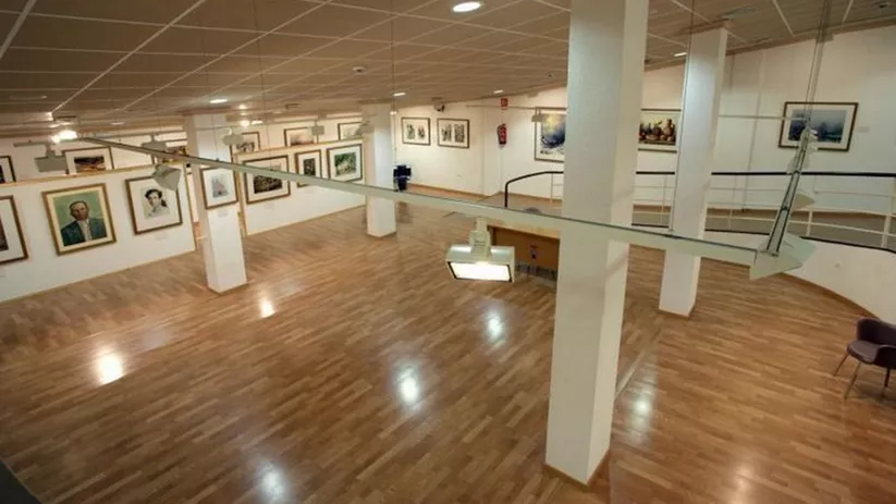 Vista elevada de galería con paredes blancas y cuadros expuestos.