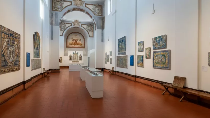 Galería larga con azulejos decorativos en las paredes y vitrinas centrales.
