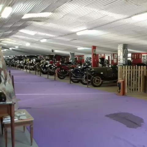 Exposición de coches y motos antiguas en sala cubierta.