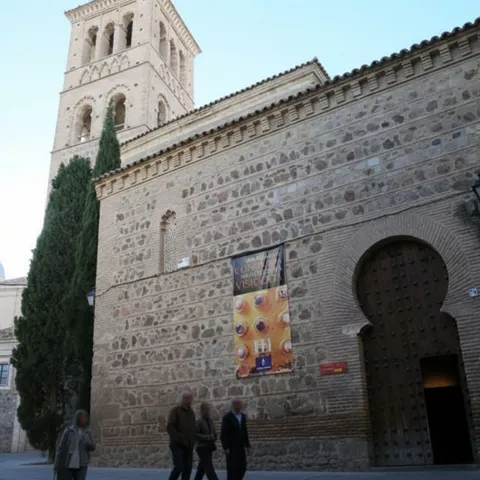 Fachada de iglesia de piedra con torre y puerta de arco de herradura.