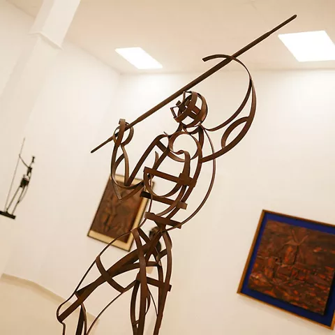 Escultura metálica de figura con lanza elevada