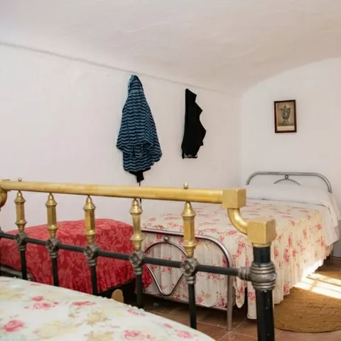 Dormitorio sencillo con camas de hierro y colchas estampadas.