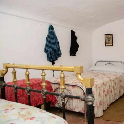 Dormitorio rústico con camas de hierro y mobiliario sencillo.