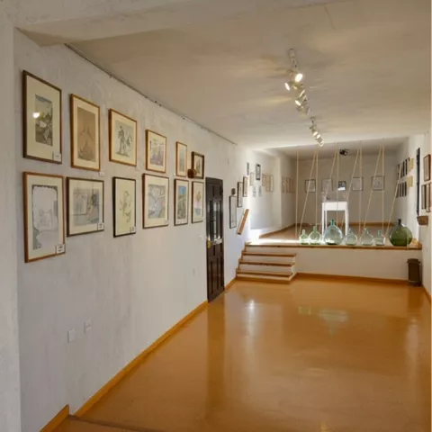 Sala de exposición con ilustraciones enmarcadas y suelo color ocre.