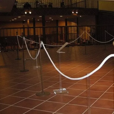 Espacio expositivo con cuerdas de protección y motocicletas en una entreplanta.