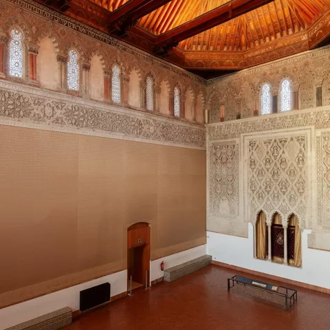 Vista lateral de sala con ornamentación mural y ventanas altas.