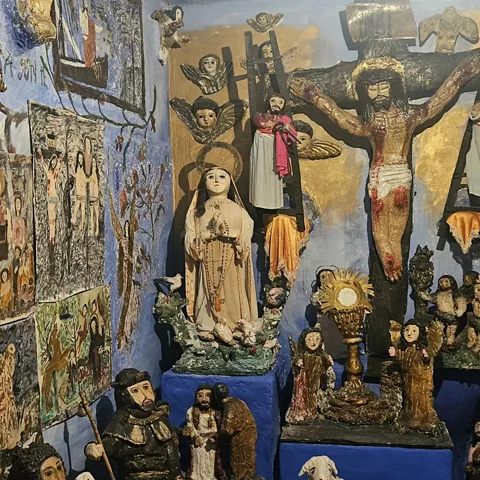 Altar popular con figuras religiosas y paredes pintadas de azul
