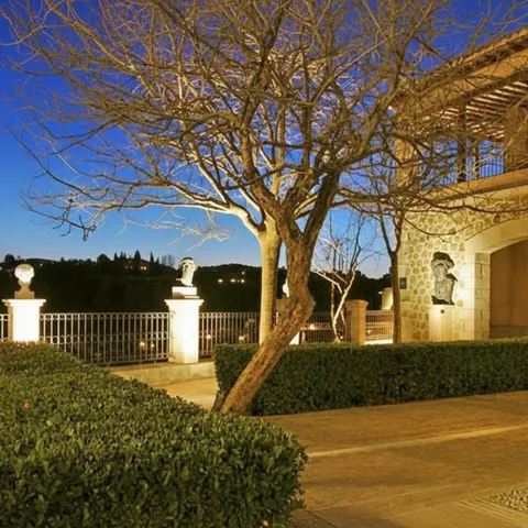 Terraza iluminada al anochecer con bustos y vistas al río.