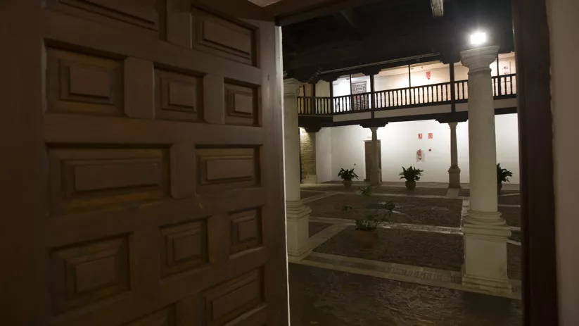 Acceso desde una puerta de madera a un patio porticado interior