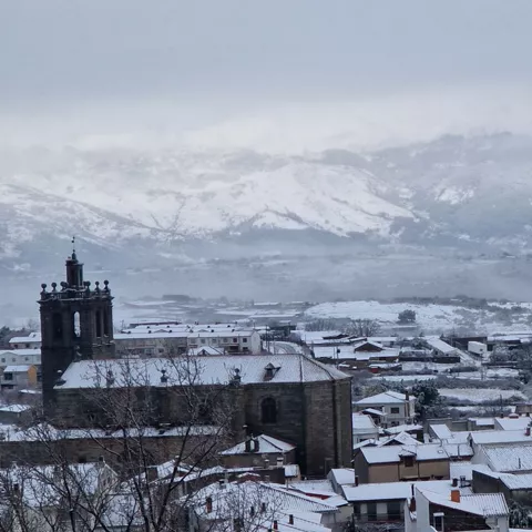 Pueblo nevado con iglesia y montañas cubiertas de nieve