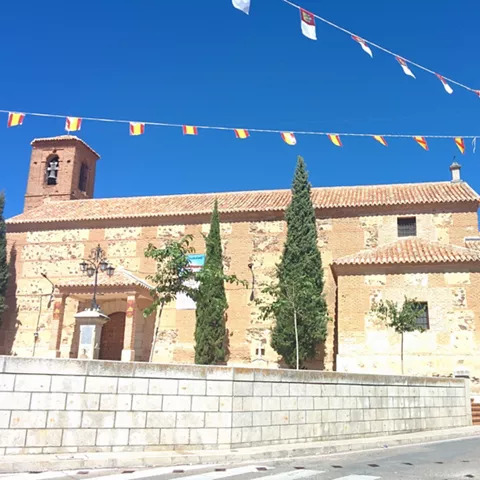 Iglesia de ladrillo y piedra con campanario y cipreses