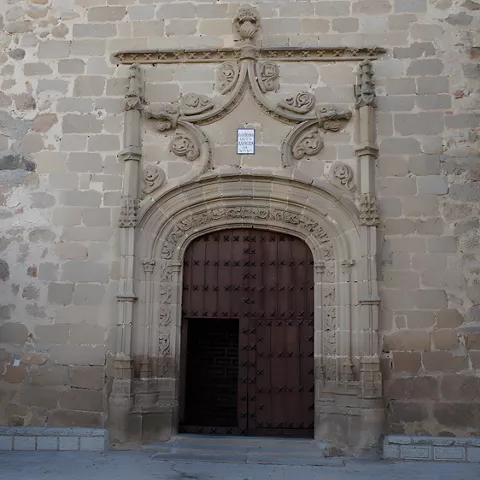 Detalle de portada de piedra tallada con gran puerta de madera