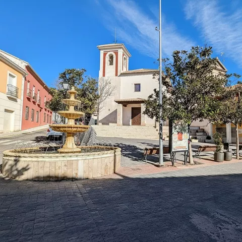 Plaza con fuente, árboles e iglesia de fachada clara