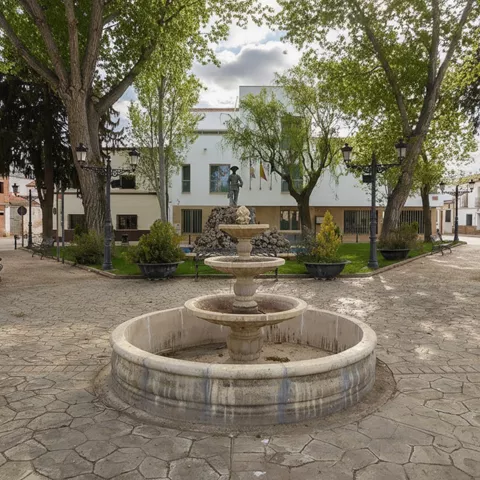 Fuente circular en plaza ajardinada con arbolado