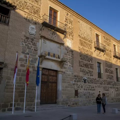 Fachada de palacio renacentista con balcones de hierro y puerta monumental.