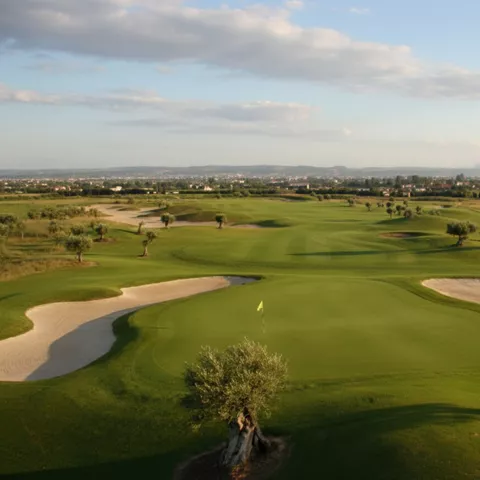 Green con bandera y bunkers de arena, con paisaje abierto al fondo.