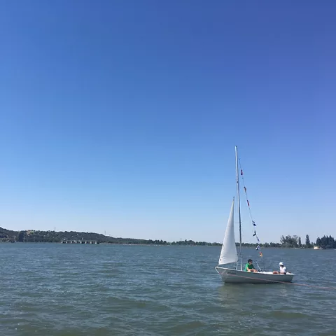 Velero navegando en un lago bajo un cielo despejado.