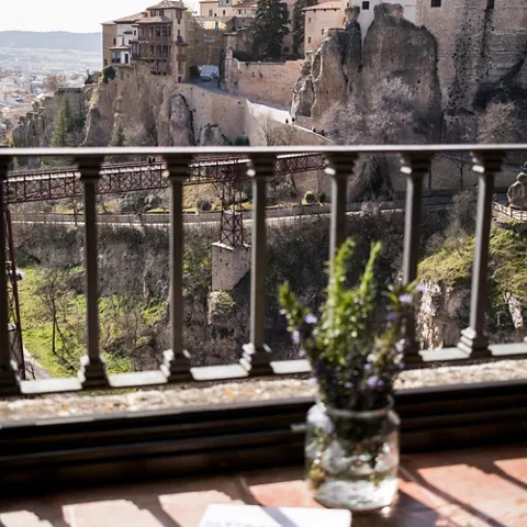 Casas colgadas sobre roca junto a pasarela metálica.