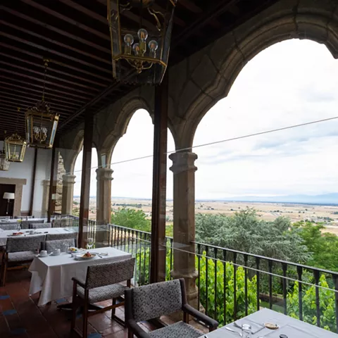 Terraza porticada con mesas y paisaje al fondo