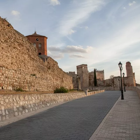 Muralla de piedra junto a un paseo con farolas