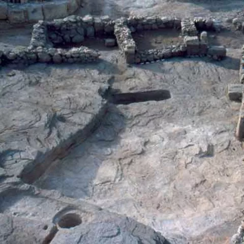 Restos arqueológicos de muros de piedra sobre una superficie excavada en la roca