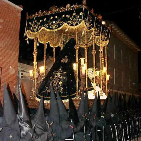 Paso procesional con figura cubierta y palio iluminado de noche