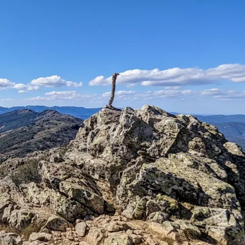 Conjunto de rocas en primer plano con cordillera y valle amplio al fondo.