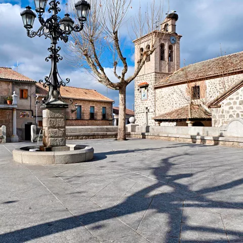 Plaza tradicional con fuente central y edificios de piedra.