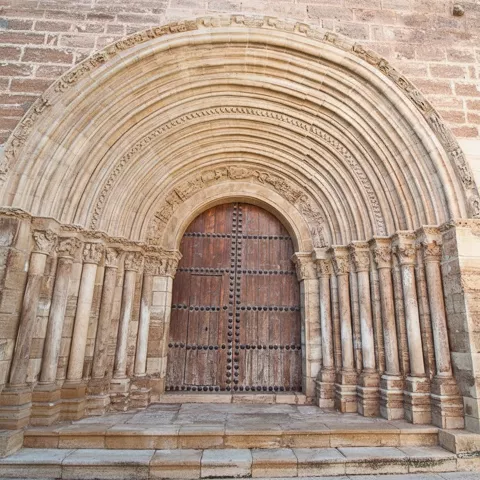 Puerta antigua enmarcada por columnas y relieves de piedra.