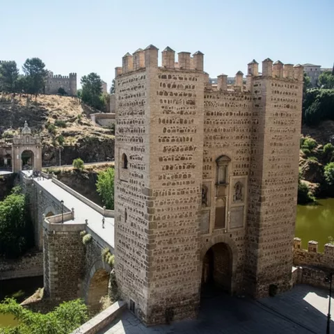 Puerta fortificada junto a puente de piedra sobre el río