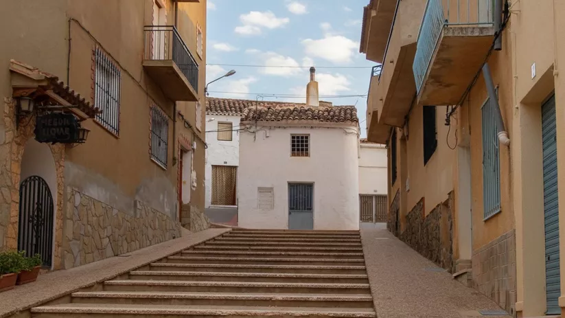 Calle de Povedilla con escaleras centrales y casas de fachadas claras.