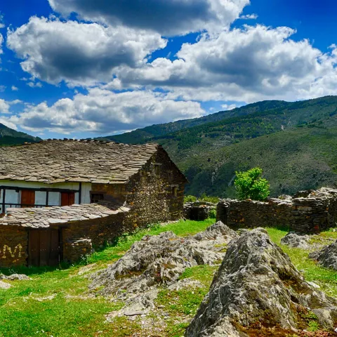 Vivienda rural de piedra rodeada de rocas y montañas.